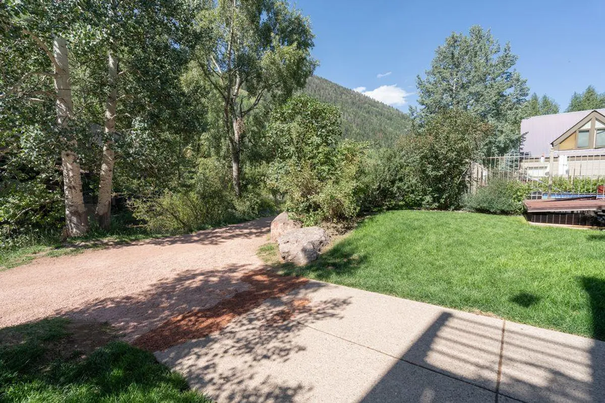 A wide, tranquil pathway framed by lush greenery and offering a striking mountain backdrop. The scene encourages outdoor activity, inviting residents to take peaceful walks, recharge in nature, and appreciate the scenic views just steps from home.