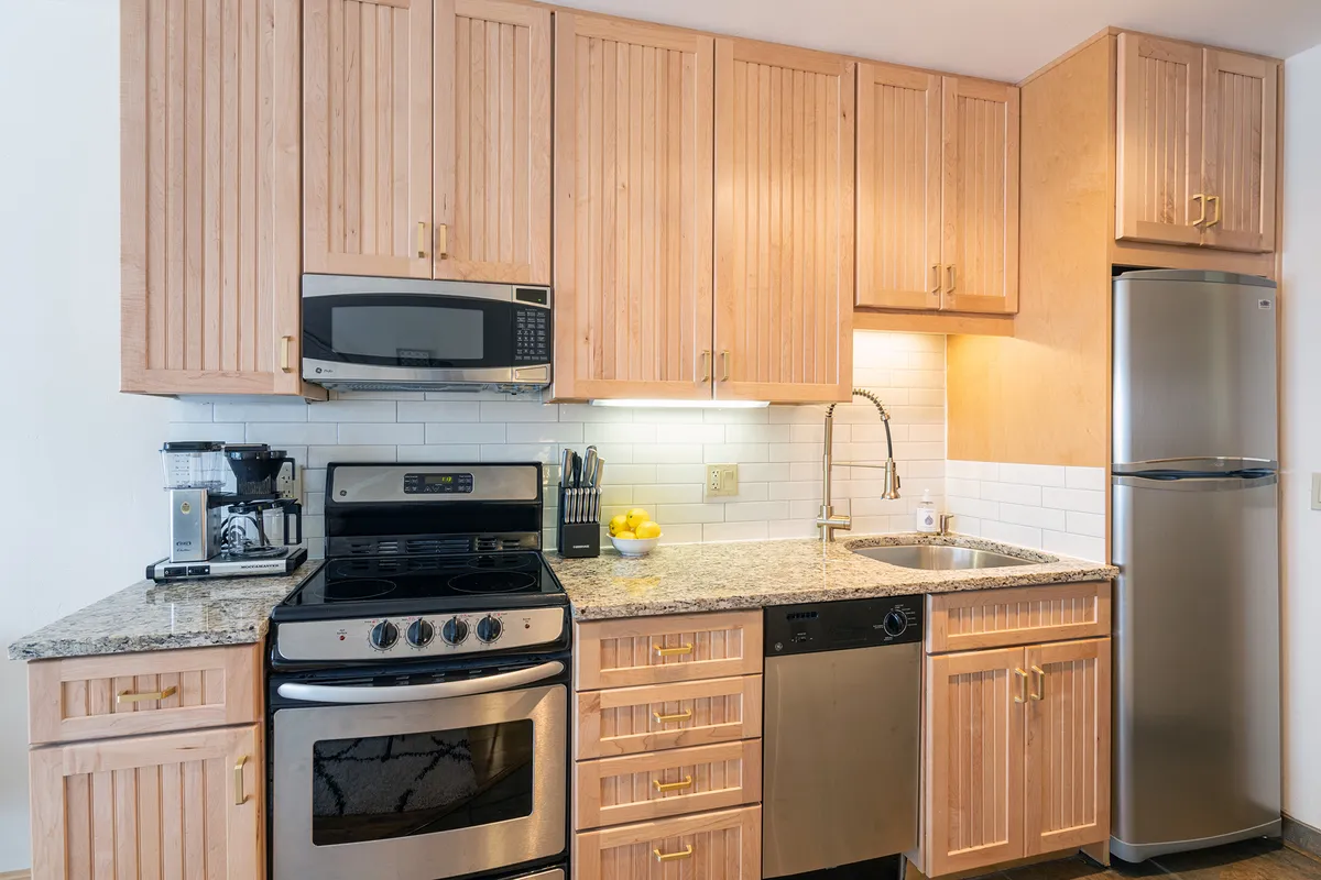 A modern kitchen is depicted with granite countertops, wooden cabinetry, and stainless steel appliances. The space feels both functional and welcoming—ready for cooking, entertaining, and family gatherings.