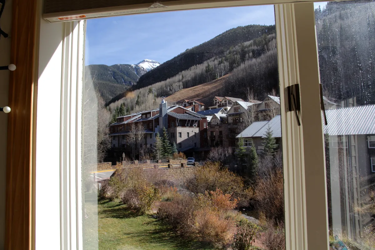 A panoramic view of the mountain range with buildings and a landscaped garden in the foreground. The serene setting presents the natural beauty guests can enjoy just outside their door, with Telluride's famed mountains always in view.